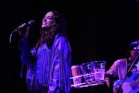 a woman in a blue jacket is holding a microphone