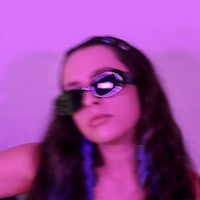 a woman wearing sunglasses in front of a purple wall