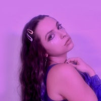 a woman with long hair posing in front of a purple background